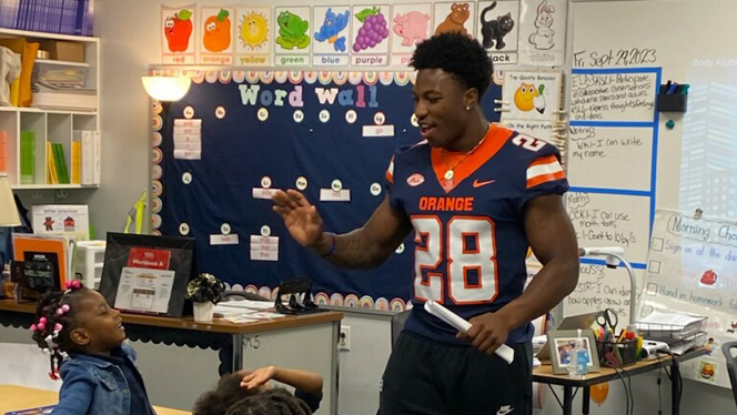 Syracuse football player gives student high five.
