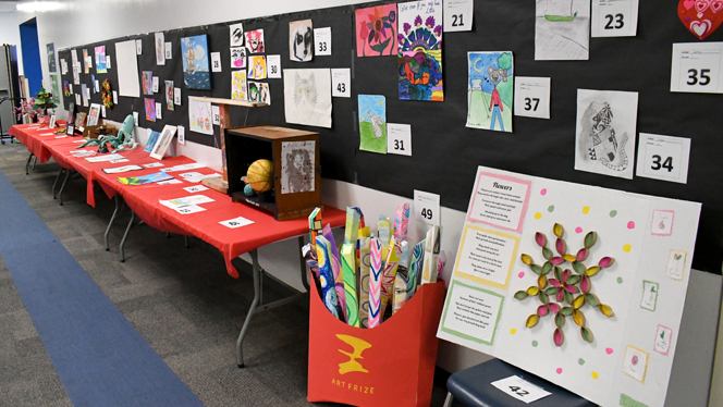 A table filled with student art exhibits.