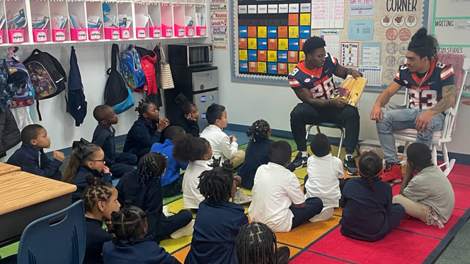 Two Syracuse football players read to group of students.