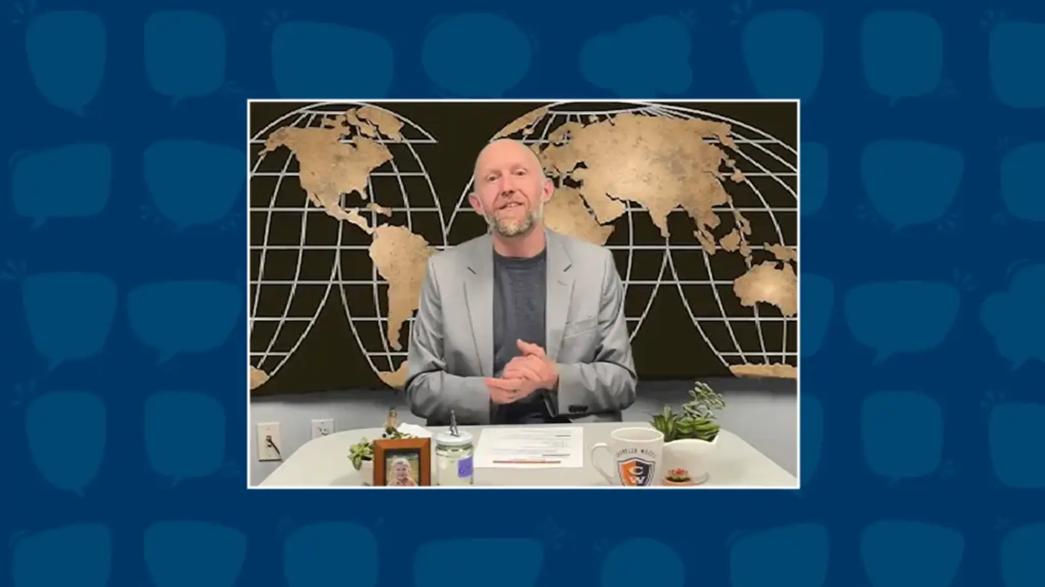 a man sitting at a desk with a map behind him