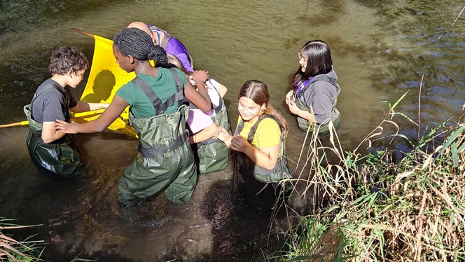 Students standing waist deep in the river.