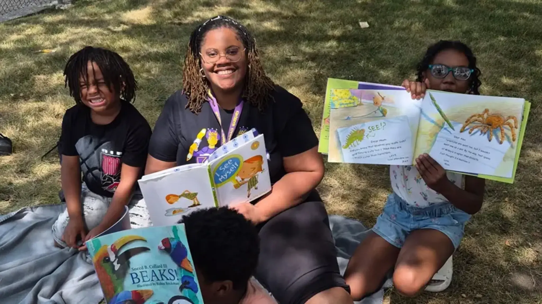 a group of people sitting on a blanket with books
