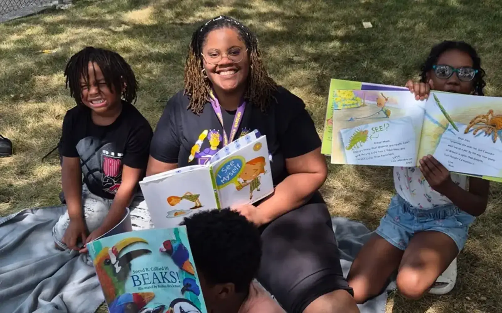 a group of people sitting on a blanket with books