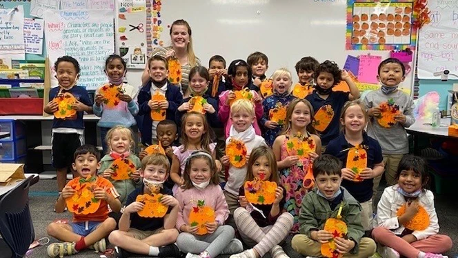 Students holding up paper pumpkins. Students holding up paper pumpkins.