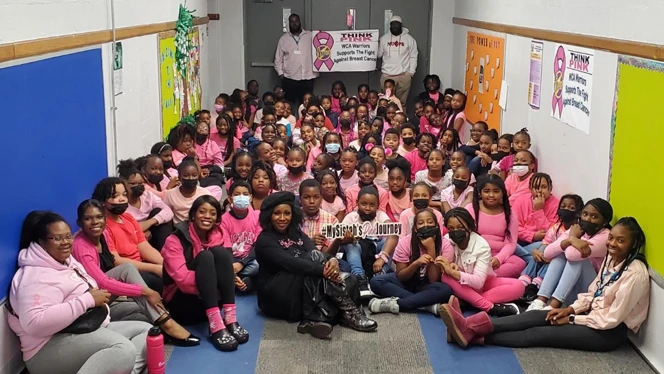 A class all wearing pink shirts smiling. A class all wearing pink shirts smiling.