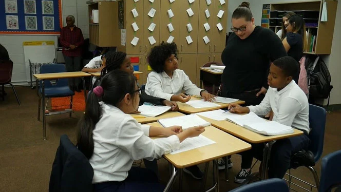 Students writing at a table. Students writing at a table.