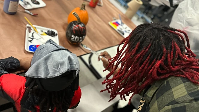 Student and parent painting pumpkin.