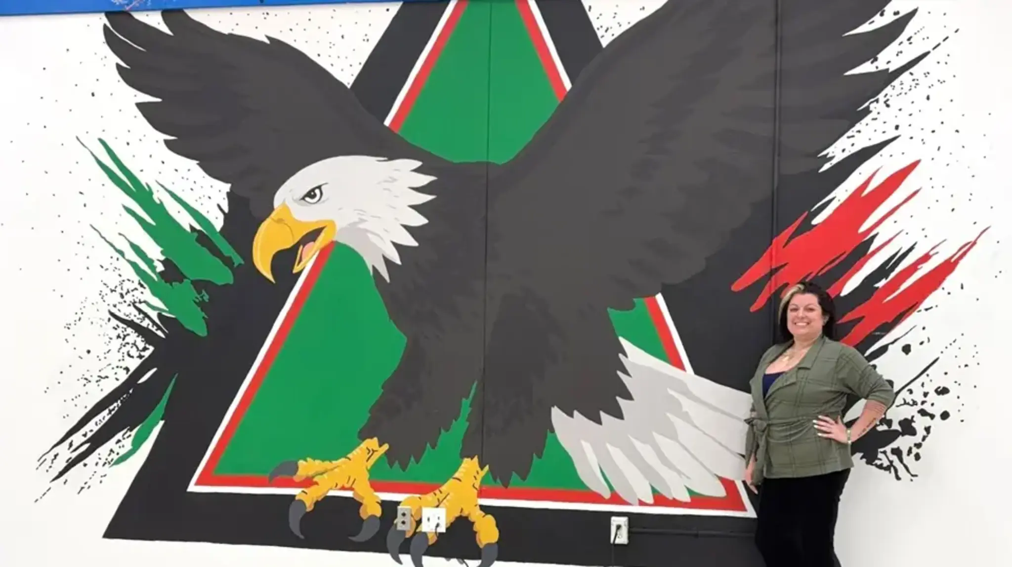 a woman standing next to a mural of an eagle
