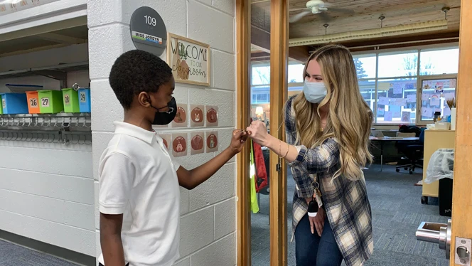 Teacher locking pinkies with a student. Teacher locking pinkies with a student.