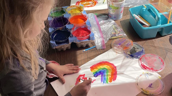 A student painting at a table. A student painting at a table.