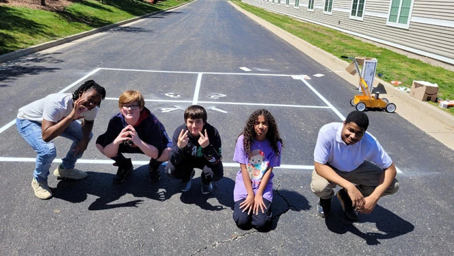 Quest students posing by four square court