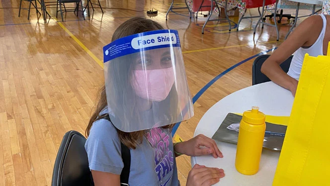 A student wearing a face mask and face shield. A student wearing a face mask and face shield.