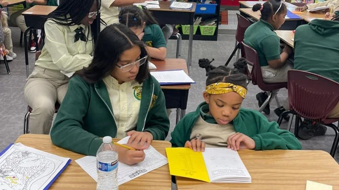 Middle school student working with younger student.