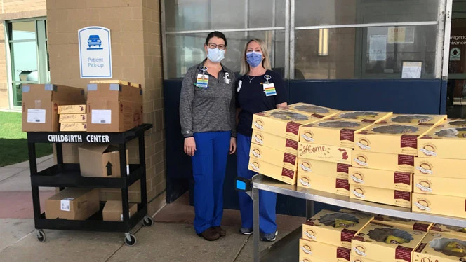 Women standing next to boxed lunches. Women standing next to boxed lunches.