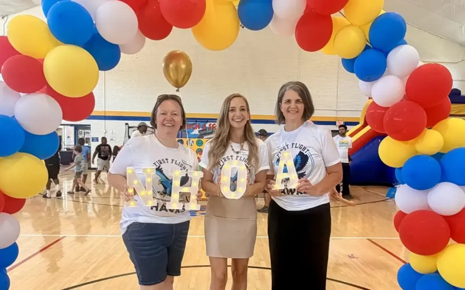 a group of women holding letters in front of a balloon arch