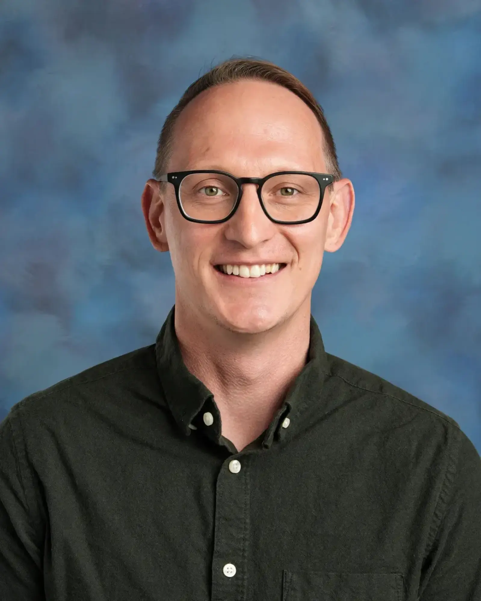a man wearing glasses and smiling
