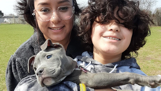 Two children holding a puppy.