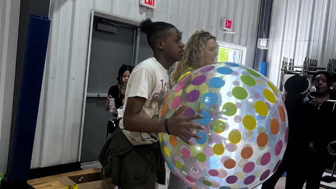 Teens playing with an inflatable ball.