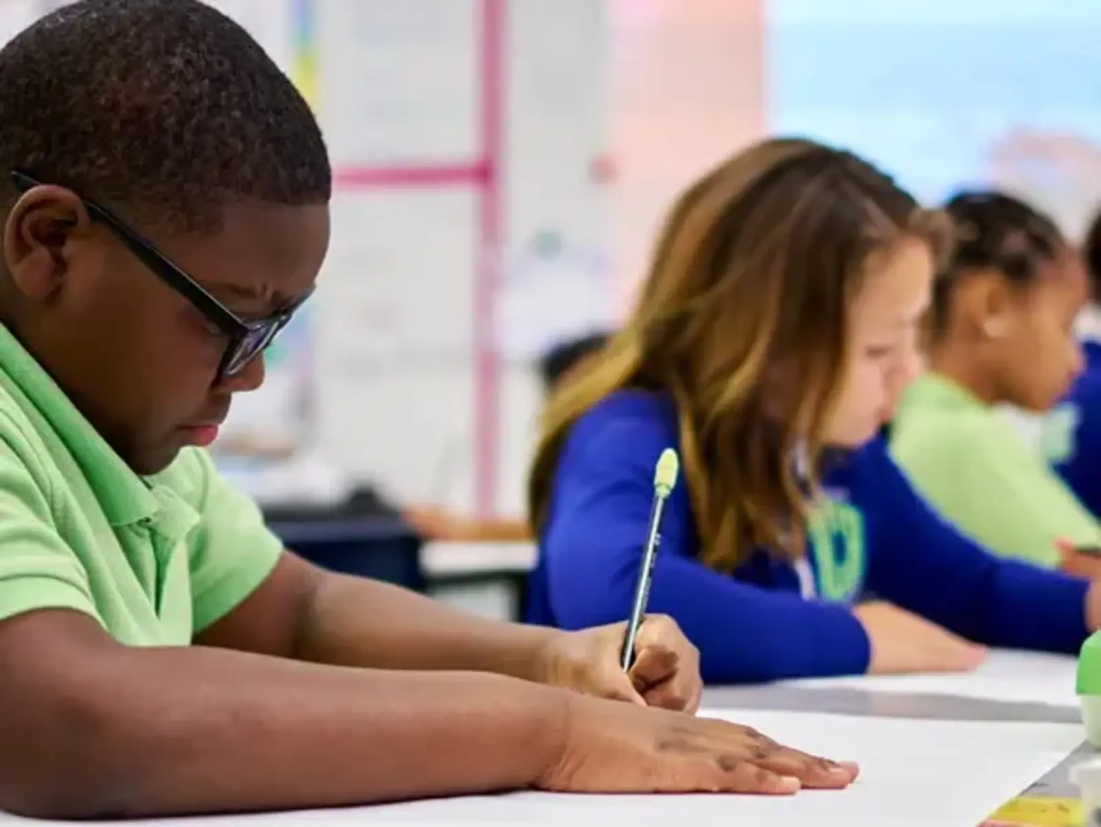 Students in green and blue shirts working at desks