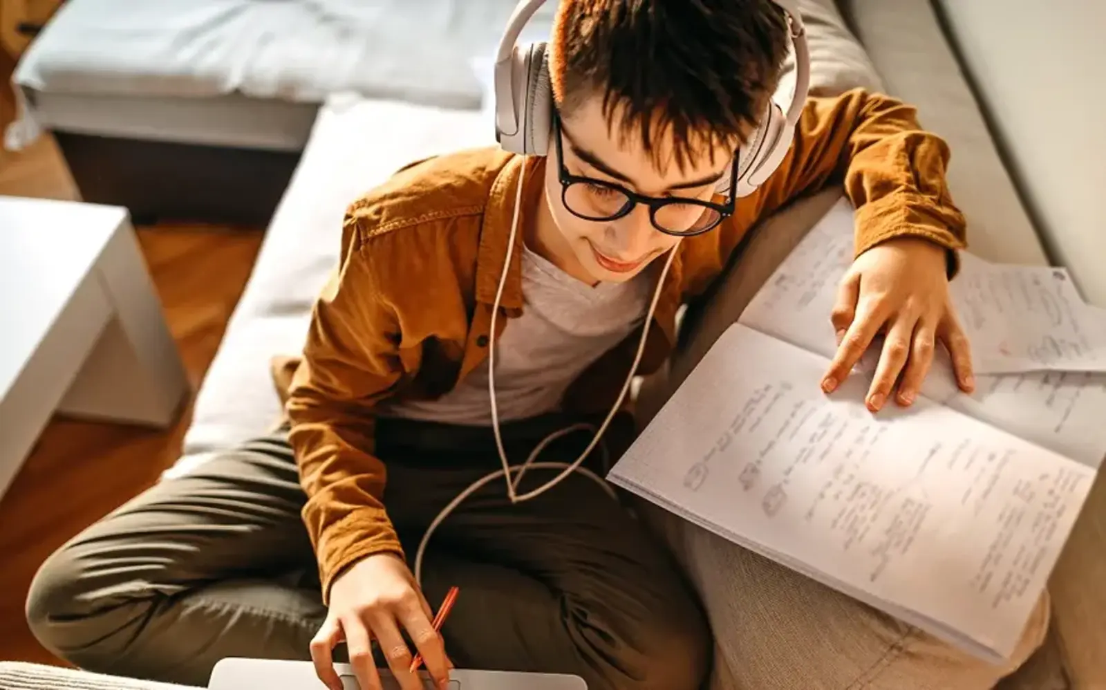 a boy wearing headphones and writing on a notebook