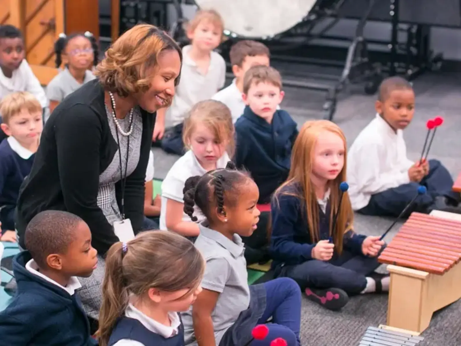 Students sitting in group on floor in music class.