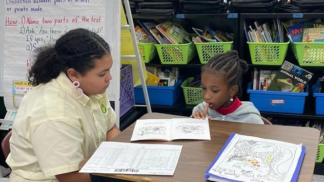 Middle school student working with younger student.