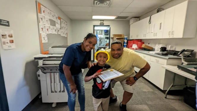 A child in a hard hat with their parents. A child in a hard hat with their parents.