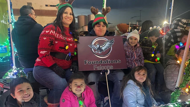K-8 School in Brighton: Staff, students, and parents from Foundations Academy sit on float in parade.