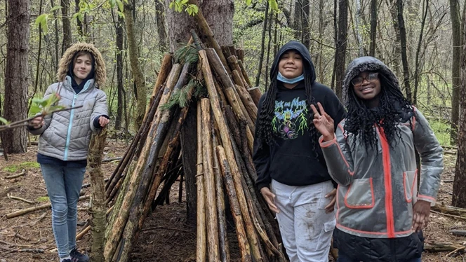 Students posing next to a shelter they made. Students posing next to a shelter they made.