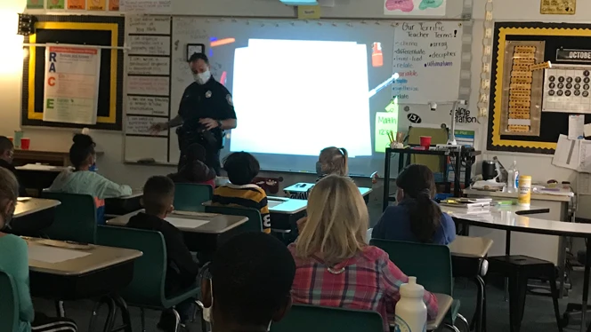 Police officer talking to class.