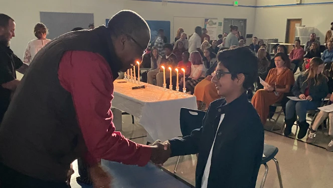 Boy shaking a mans hand.