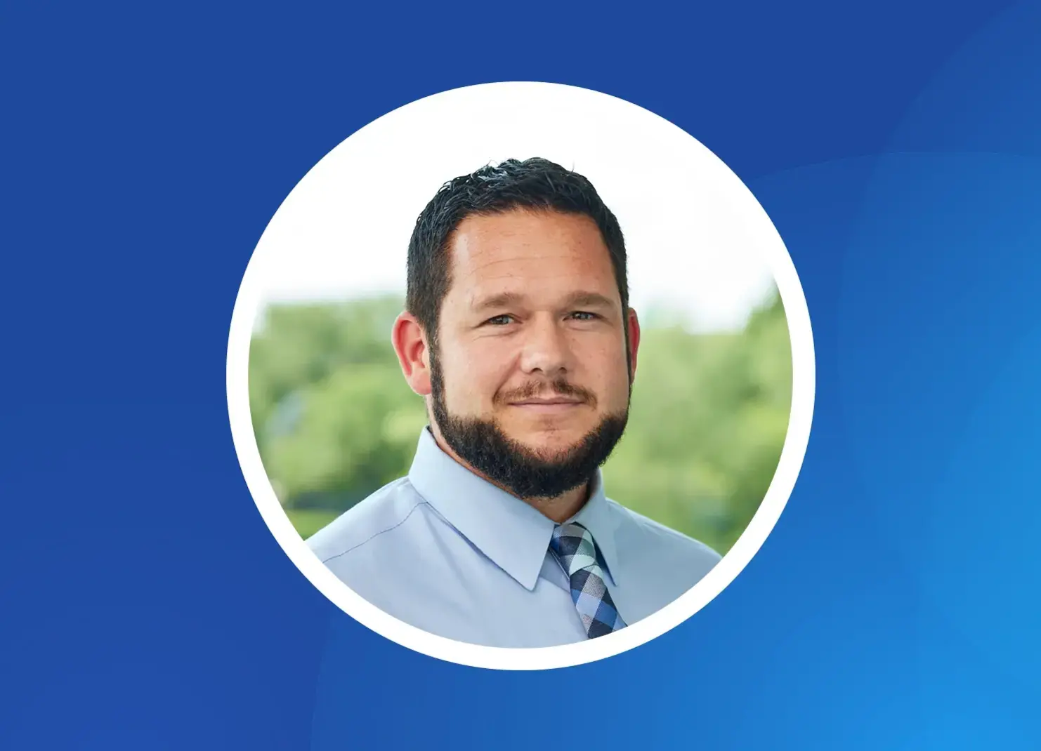 a man with a beard wearing a blue shirt and tie