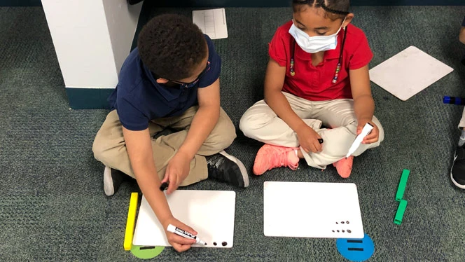Children writing on a whiteboard. Children writing on a whiteboard.