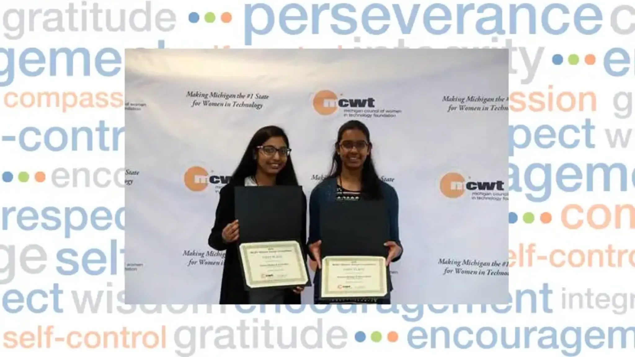 Two females holding awards