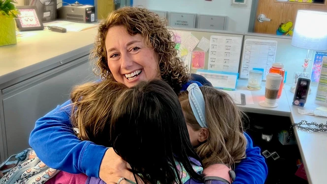 Christina Hasselkus smiling and hugging her students Christina Hasselkus smiling and hugging her students