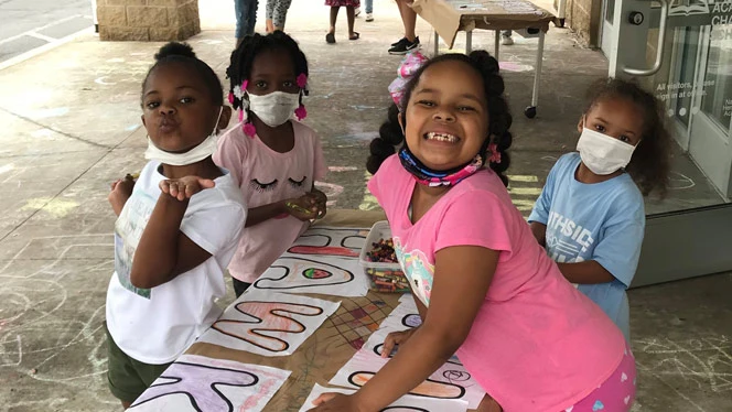 Children smiling and drawing at a table Children smiling and drawing at a table