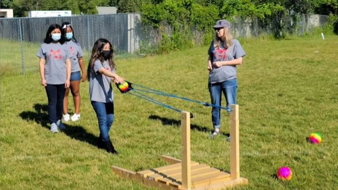 Student launching a ball using a slingshot. Student launching a ball using a slingshot.
