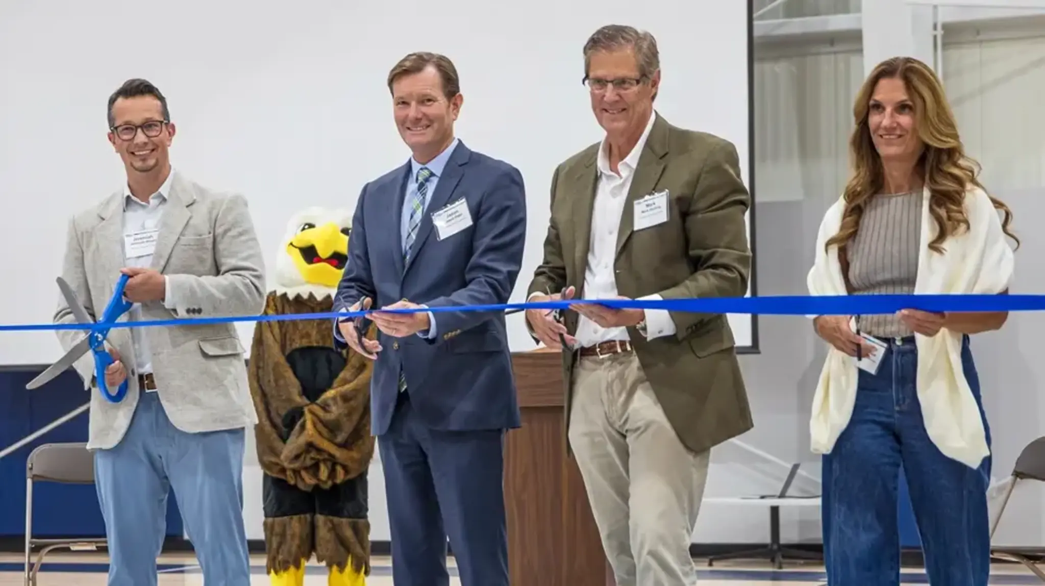 a group of people cutting a ribbon
