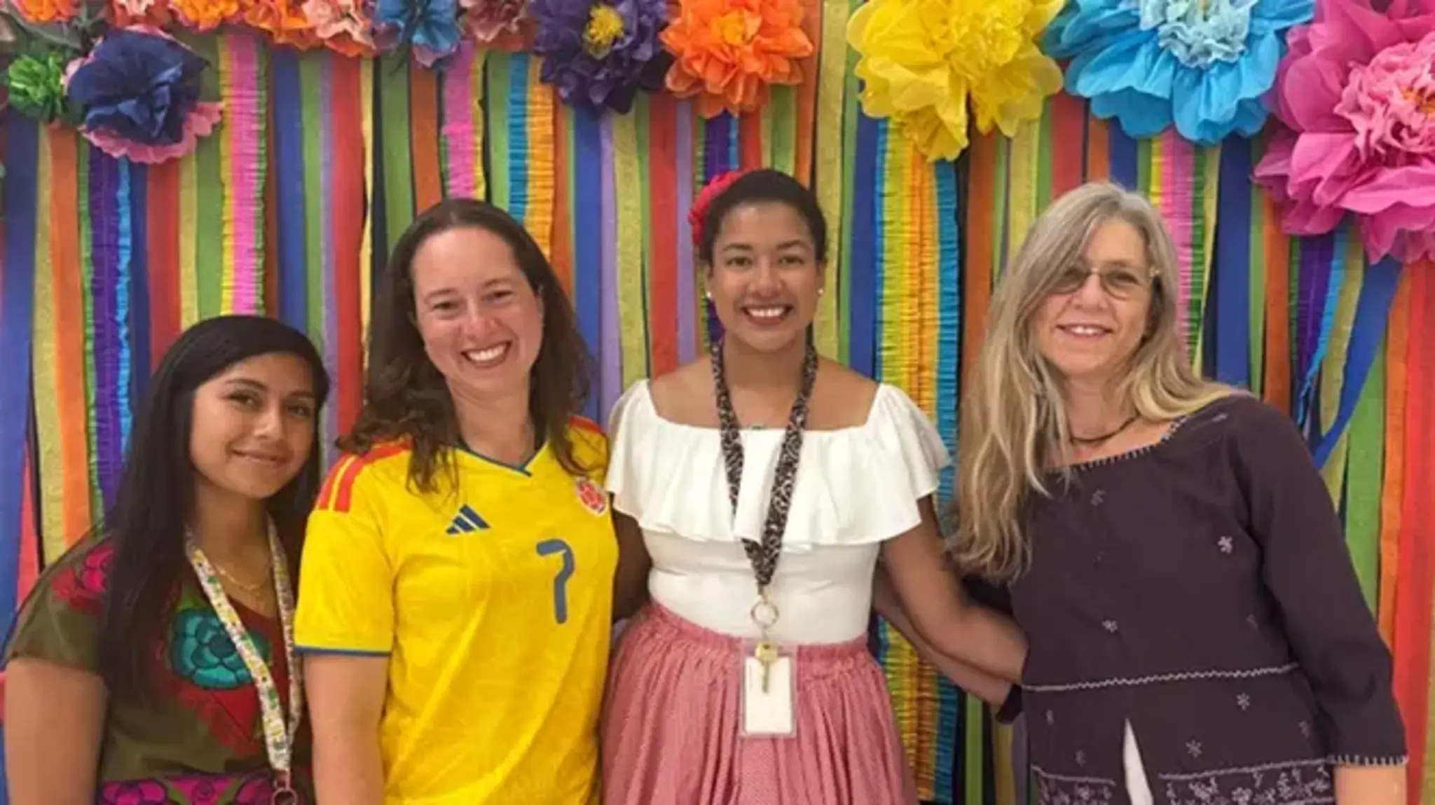 a group of women standing in front of a rainbow wall
