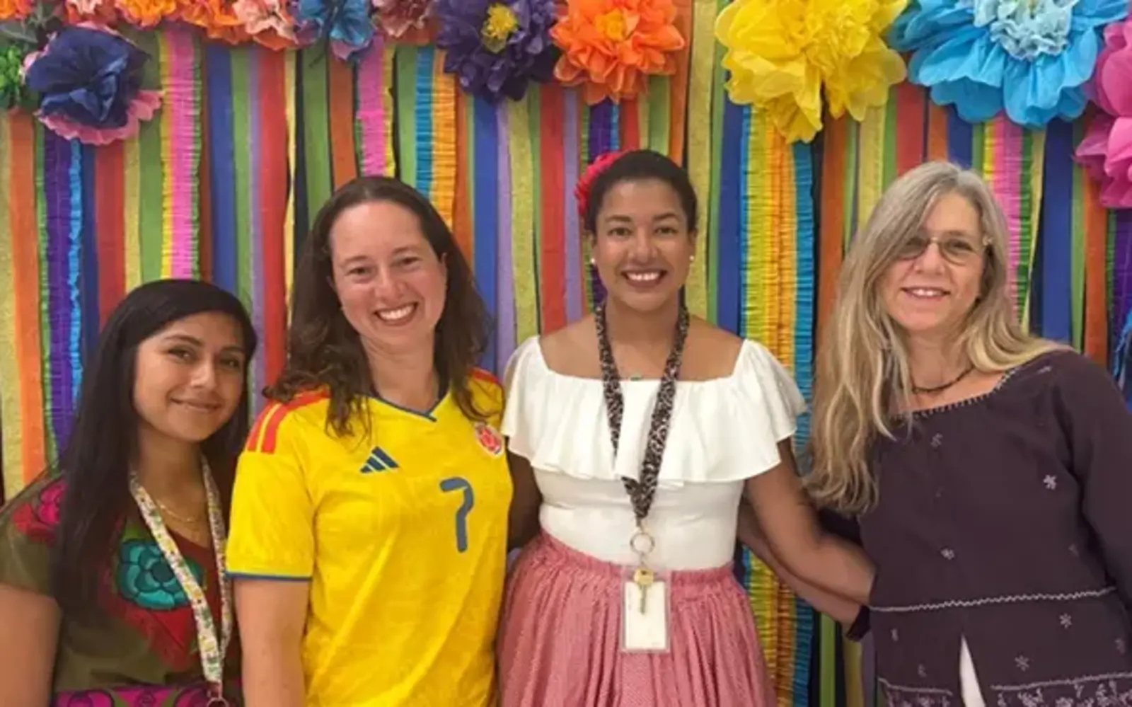 a group of women standing in front of a rainbow wall