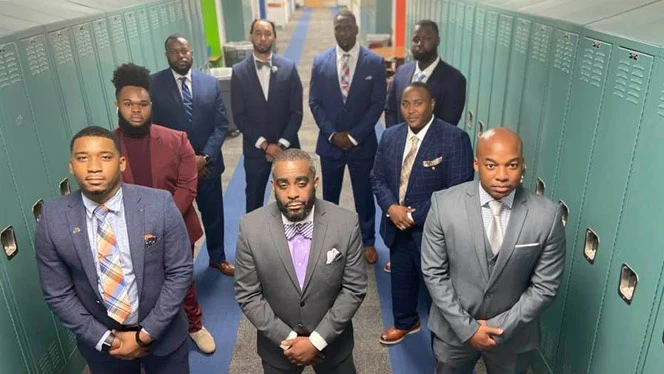 Dr Landon Brown wearing a suit with others. Dr Landon Brown wearing a suit with others.
