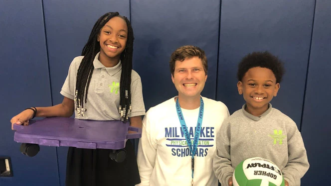 K-8 School in Milwaukee: Students pose for photo with PE teacher Anderson.
