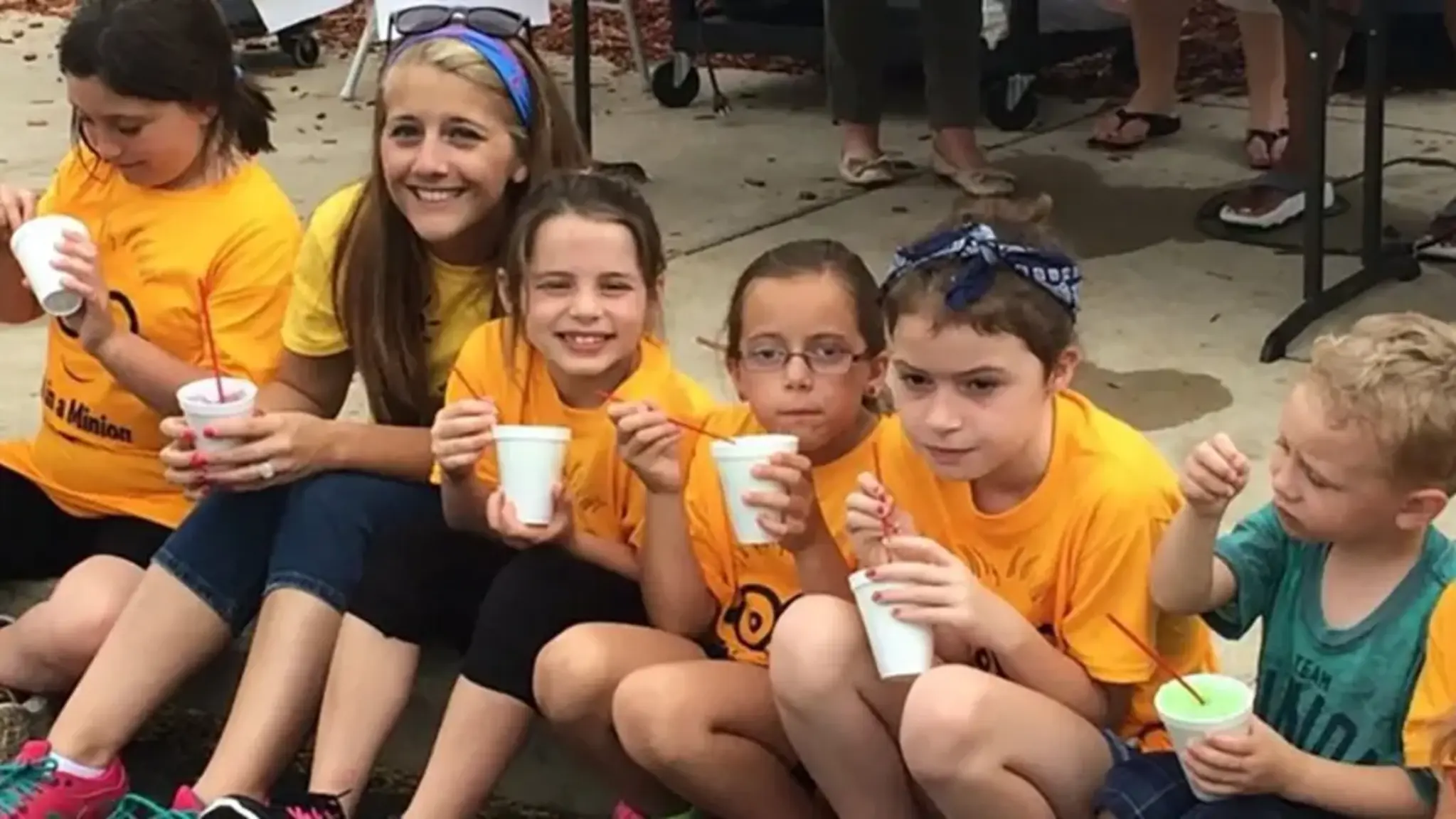 a group of kids sitting on the ground holding cups