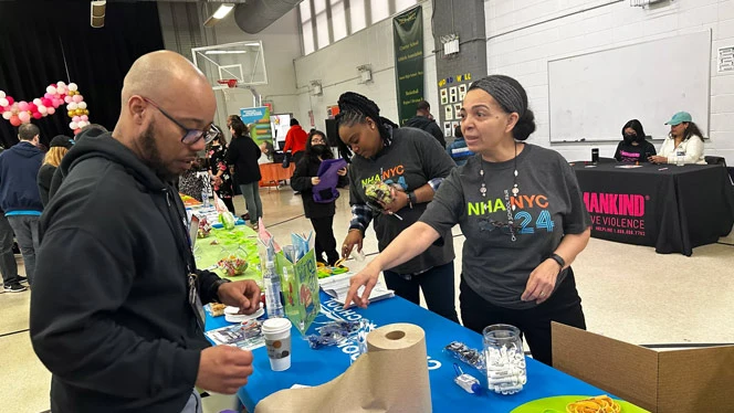 Staff at Brooklyn Scholars charter school fair booth talking with parent