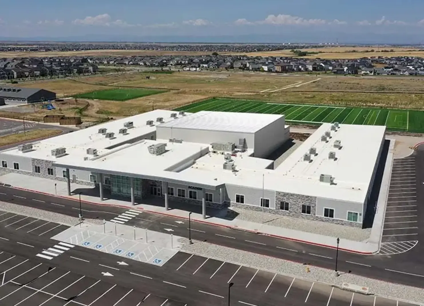 a building with a parking lot and a large field