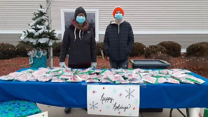 Adults standing in the cold at a gift table. Adults standing in the cold at a gift table.