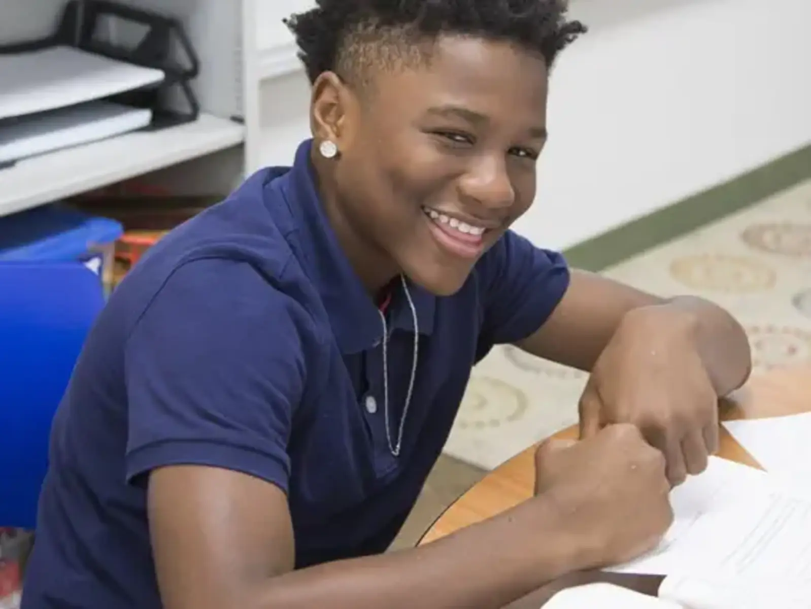 K-8 School in Toledo: Student smiling at desk, working on class work.