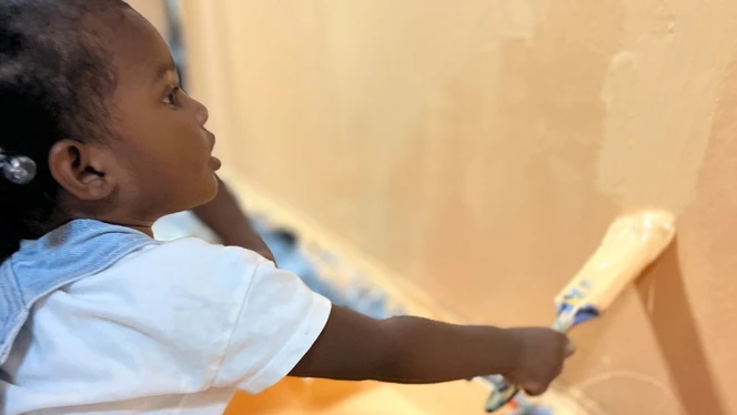 Small child painting wall.