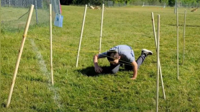Student crawling under wire. Student crawling under wire.