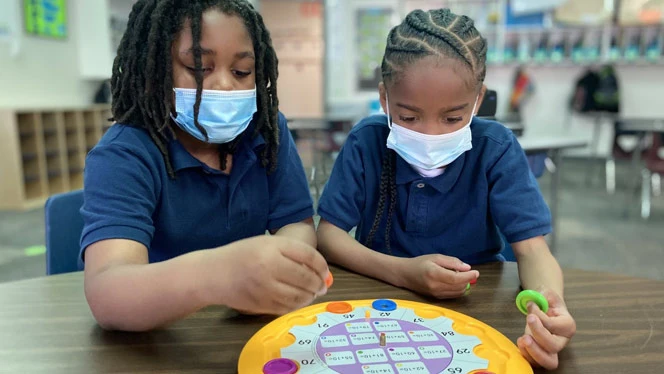 Students playing at a table. Students playing at a table.